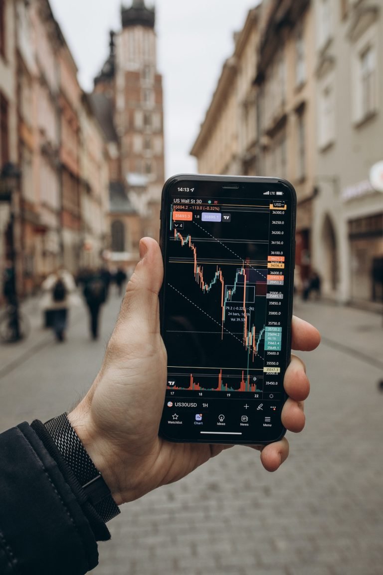 A smartphone showing a financial trading app with live charts, highlighting the journey to financial freedom through investing.