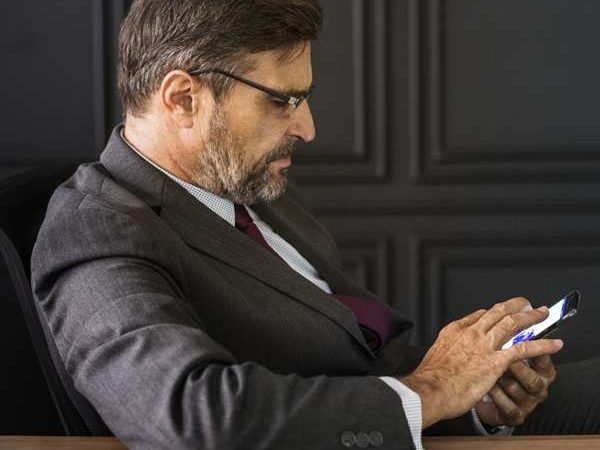 Businessman wearing a black coat using his mobile