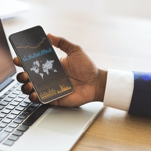 Black businessman checking global financial analytic on smartphone or trading on forex