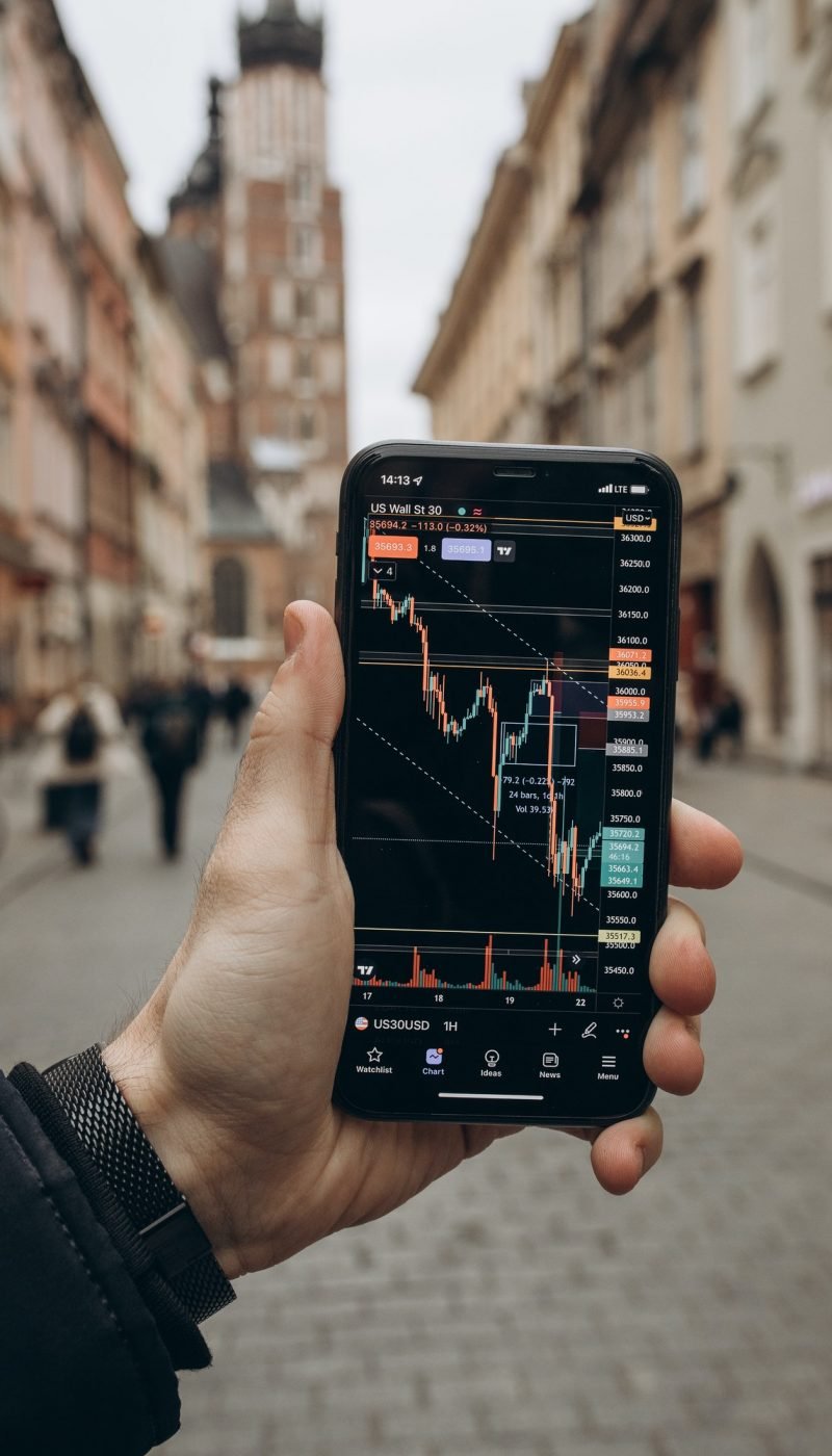 A smartphone showing a financial trading app with live charts, highlighting the journey to financial freedom through investing.