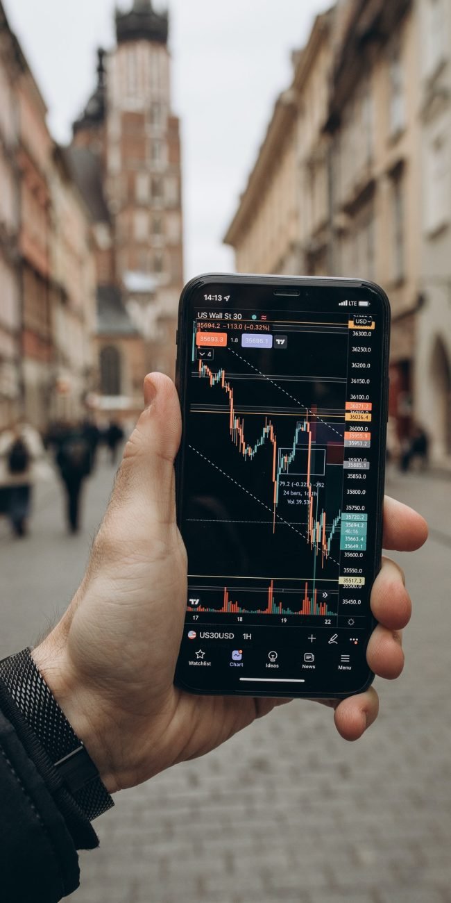 A smartphone showing a financial trading app with live charts, highlighting the journey to financial freedom through investing.